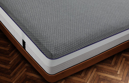 Close-up corner view of Durfi Advance Mattress Protector with light grey diamond-quilted fabric and distinctive purple piping fitted snugly over a mattress on a warm brown wooden bed frame with herringbone parquet flooring
