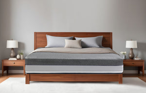 Durfi Advance Mattress Protector with grey diamond-quilted surface fitted over a mattress on a warm walnut wood bed frame in a minimal grey bedroom with matching wooden nightstands and ceramic table lamps