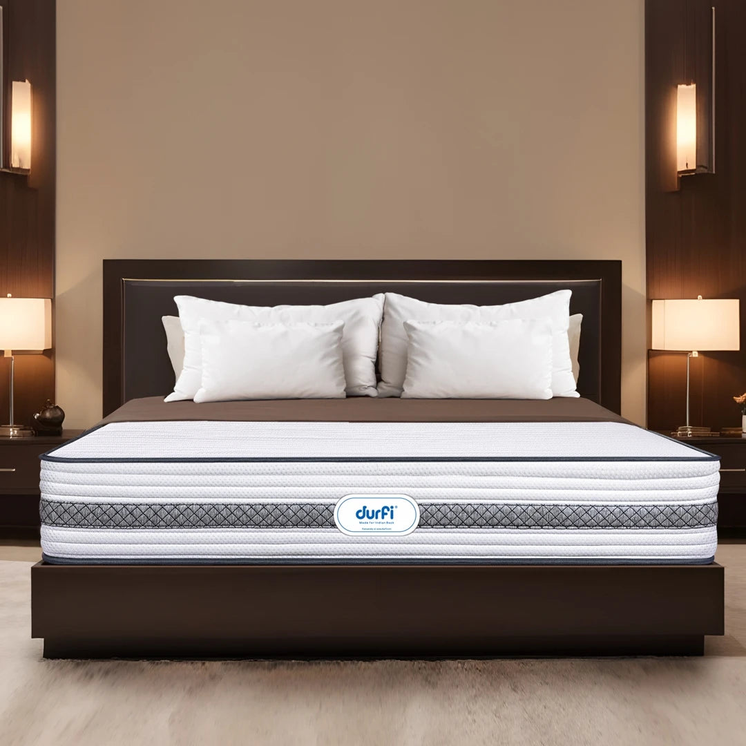 Durfi Hybrid Pocket Spring Mattress placed on a dark wood bed frame in a warm-toned luxury bedroom with wall-mounted lamps and white pillows