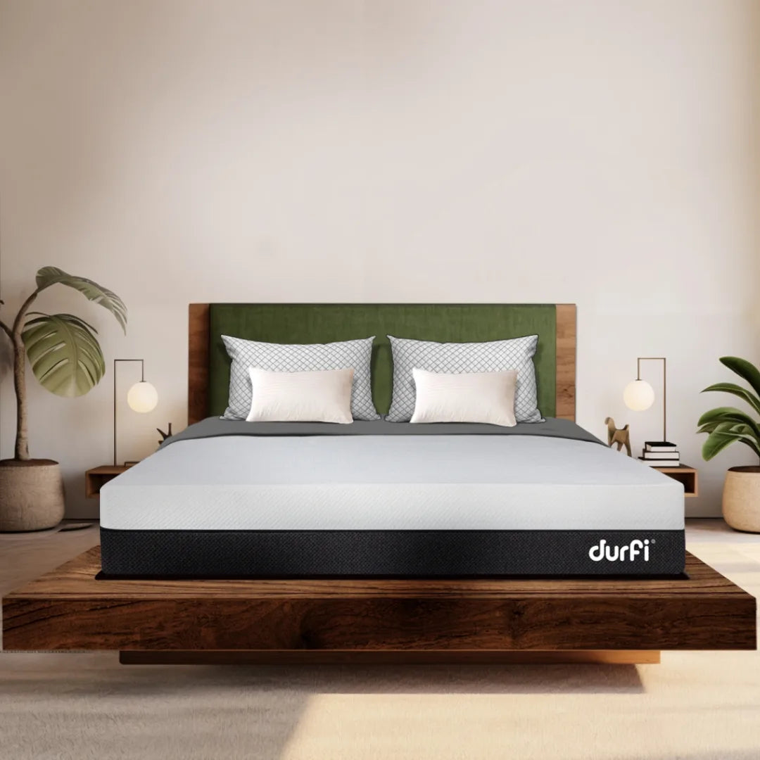 Durfi Natural Latex Ortho Mattress placed on a rustic wooden platform bed in a bright, nature-inspired bedroom with indoor plants and pendant lamps