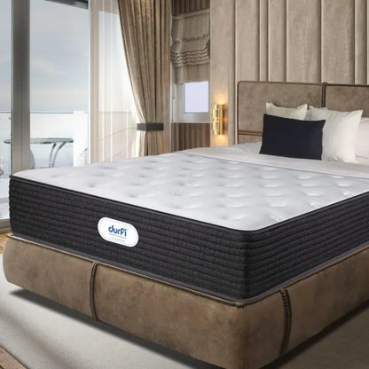 Durfi Ortho Flex Hybrid Mattress shown at an angle on a tan suede bed frame in a premium beige-toned bedroom with floor-to-ceiling windows, gold wall sconces, and navy accent pillows