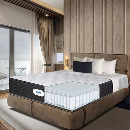 Cross-section view of Durfi Ortho Flex Hybrid Mattress on a tan suede bed in a luxury bedroom revealing the internal pocket spring and foam construction with ocean view in background