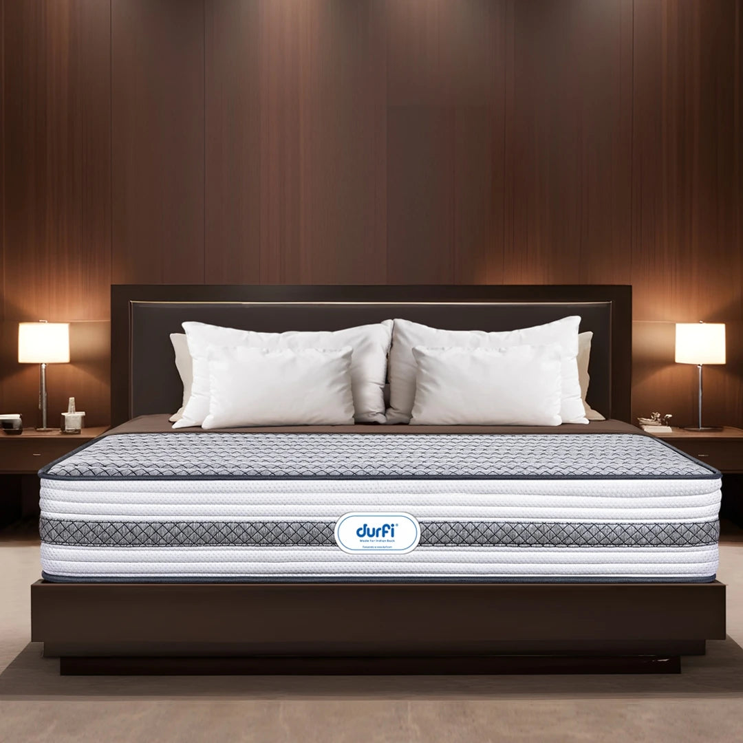 Durfi Ortho Memory Foam Mattress placed on a dark wood bed frame in a luxurious hotel-style bedroom with warm lighting and white pillows