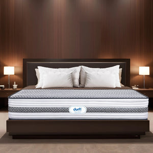 Durfi Ortho Memory Foam Mattress placed on a dark wood bed frame in a luxurious hotel-style bedroom with warm lighting and white pillows