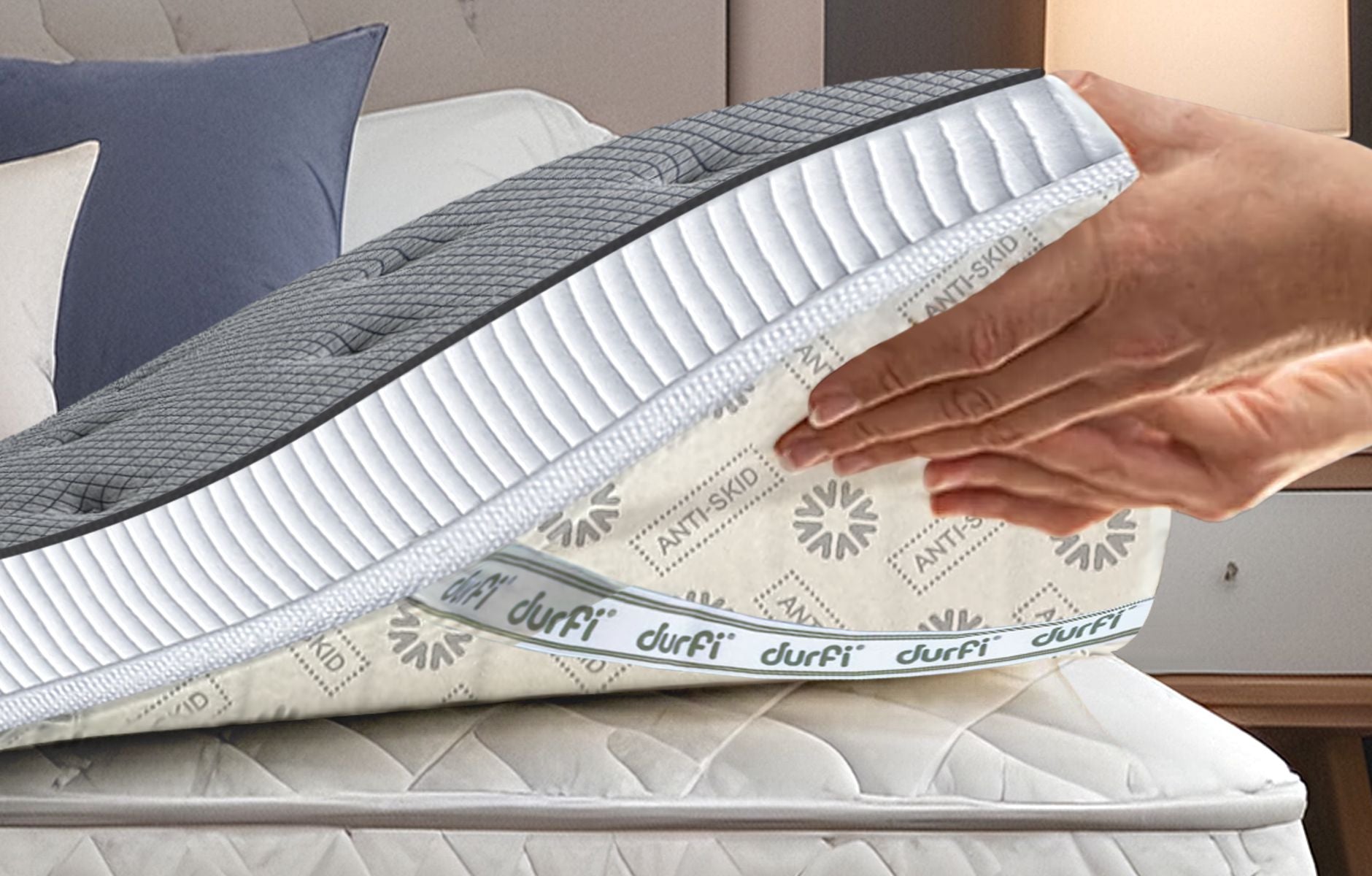Hand placing Durfi Soft Mattress Topper onto a mattress showing the anti-skid patterned base fabric with Durfi branding, demonstrating easy installation over an existing mattress