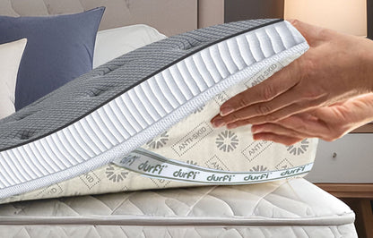 Hand placing Durfi Soft Mattress Topper onto a mattress showing the anti-skid patterned base fabric with Durfi branding, demonstrating easy installation over an existing mattress