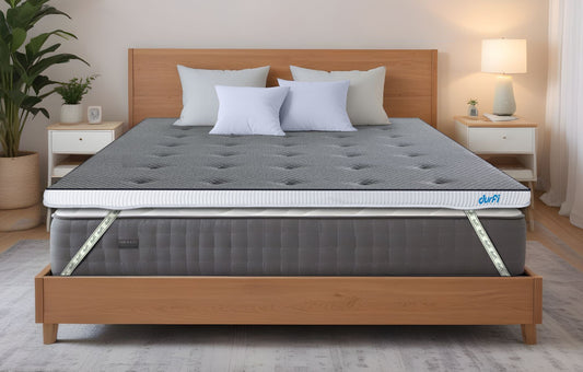 Durfi Soft Mattress Topper with grey tufted quilted surface placed over a mattress on a natural wood bed frame in a bright Scandinavian-style bedroom with indoor plants and white nightstands